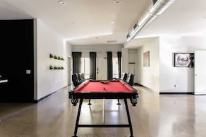 Relax in this stylish room with a pool table, comfortable seating, and a large painting on the wall.