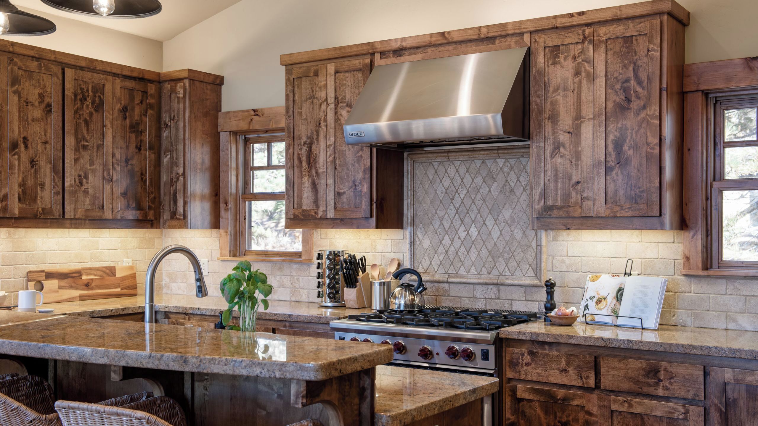 A kitchen with wooden cabinets, a stainless steel range hood, a granite countertop, and a built-in stove.