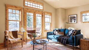 Un salon chaleureux avec un canapé bleu, des meubles en bois et de grandes fenêtres.
