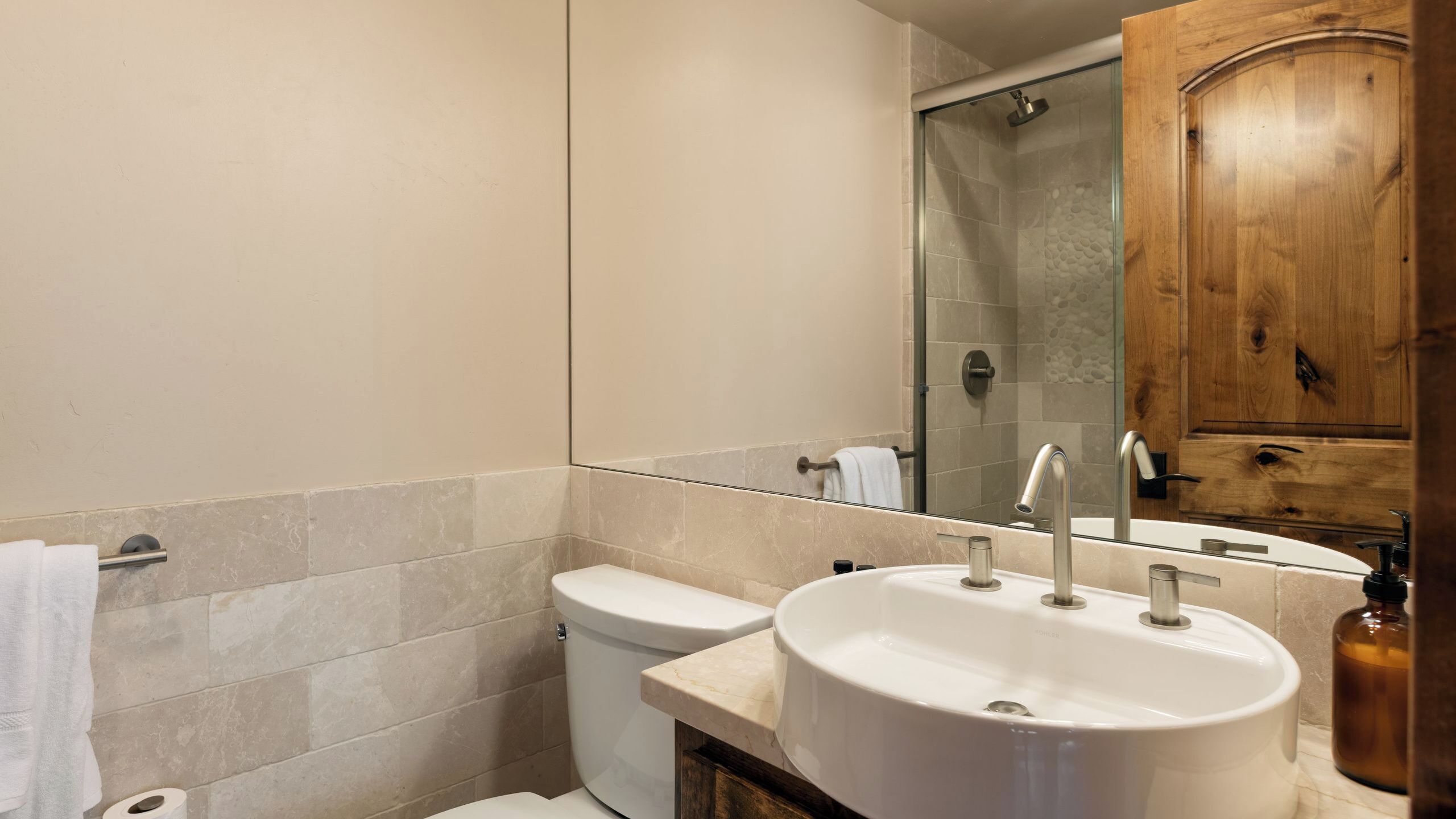 Un baño con inodoro, lavabo, espejo y ducha.