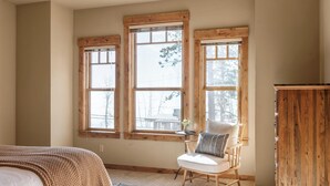 A bedroom with three windows, a chair, and a wooden cabinet. - Lakefront Home in Kings Beach w/ Views Prime Location Atkinson by Avantstay (Kings Beach)
