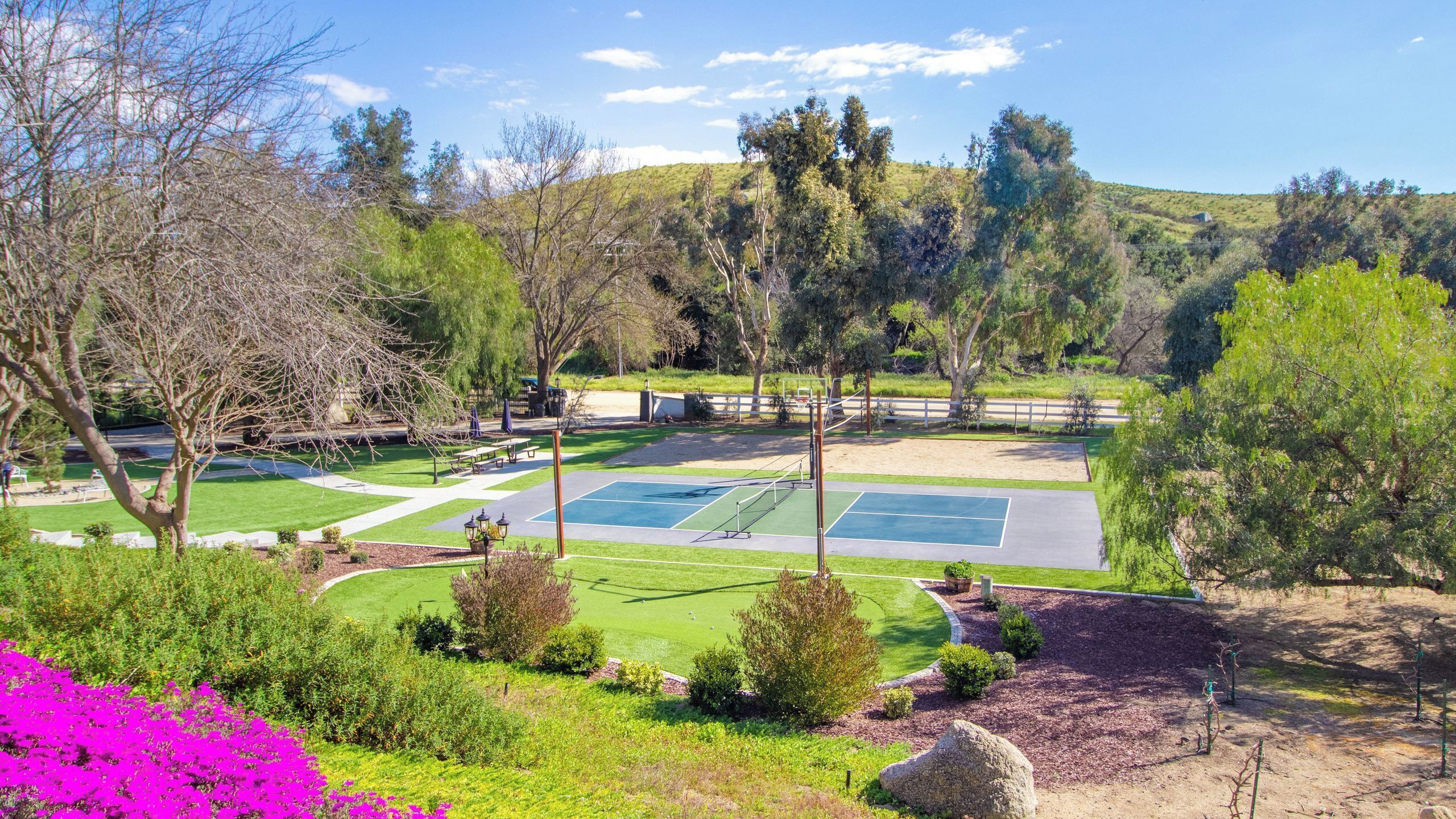 A tennis court surrounded by trees and a grassy area.