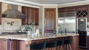 A kitchen with a large island, stainless steel appliances, wooden cabinets, and a modern design. - Luxe Scottsdale Desert Oasis Infinity Pool, Spa, Panoramic Views + Firepit (Cave Creek)