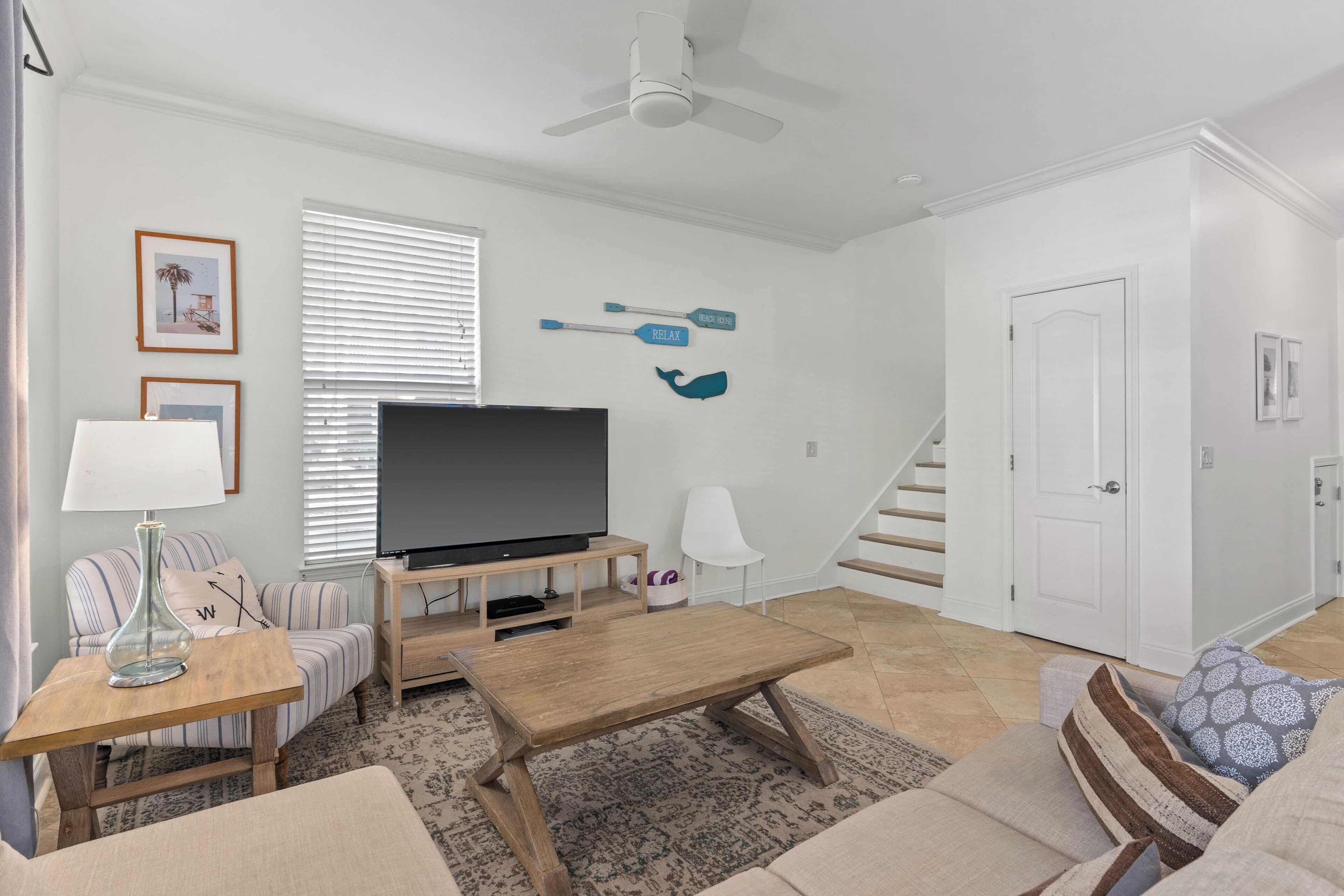 A living room with a TV, sofa, coffee table, and a staircase.