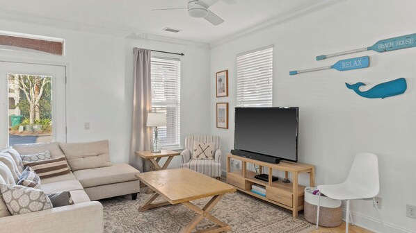 Een moderne woonkamer met een bank, salontafel, televisie en decoratieve wandkunst.