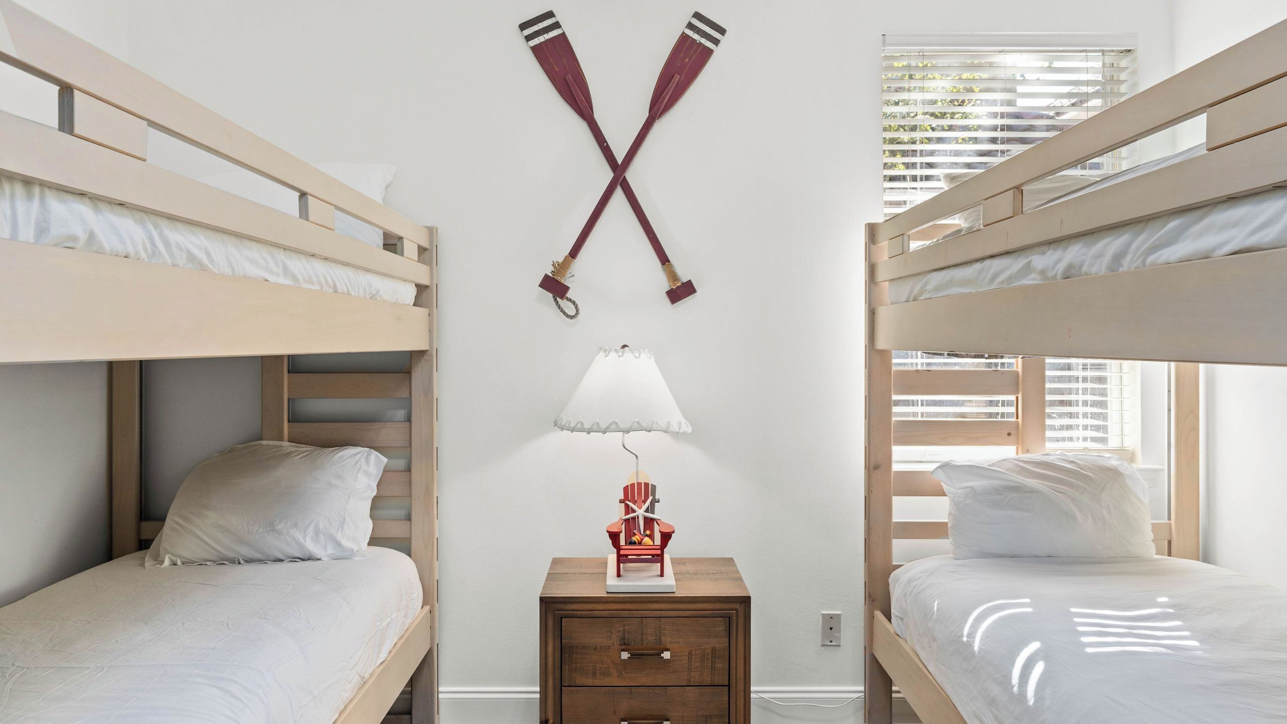 A bunk bed room with a small table, a lamp, and a wall-mounted decoration.