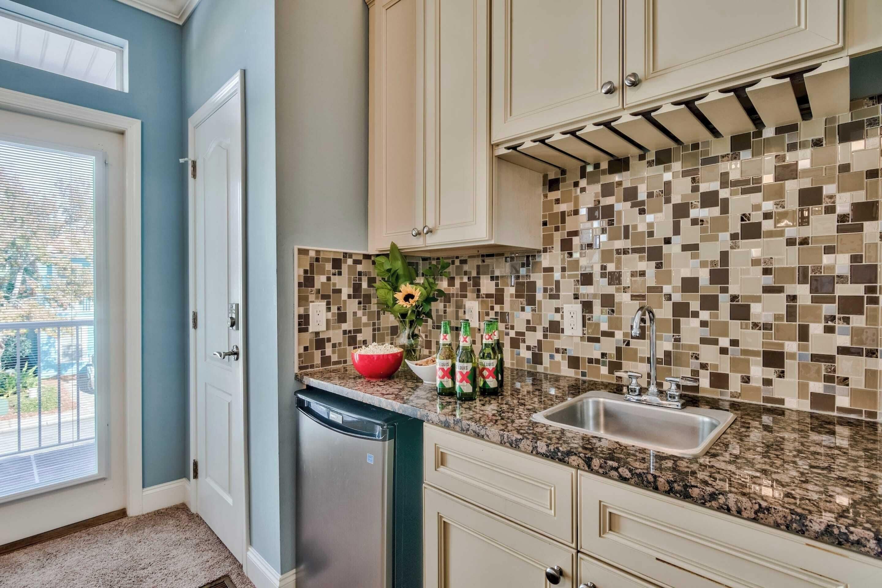 A kitchen with a dishwasher, a sink, and a tiled backsplash.
