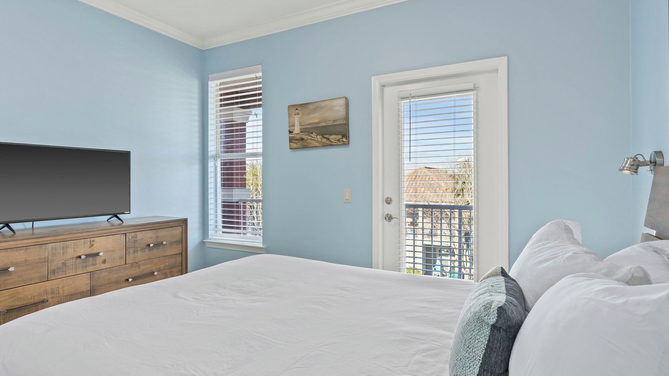 Una camera da letto con un letto, una cassettiera, una televisione e una porta con vista.