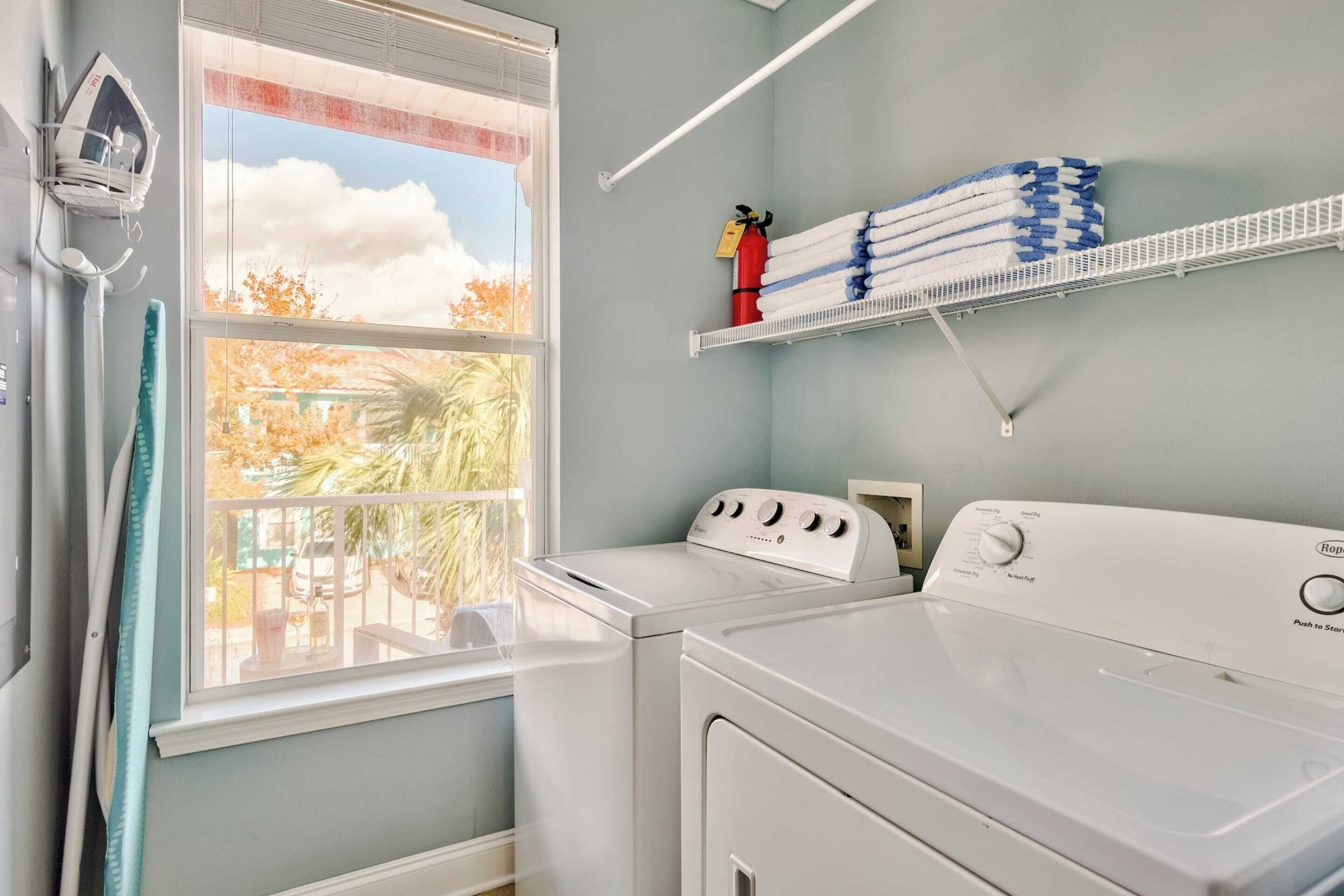 A laundry room with a washing machine, dryer, and a shelf with folded towels.
