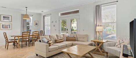 A living room with a sofa, coffee table, TV, and dining area with chairs and a table.