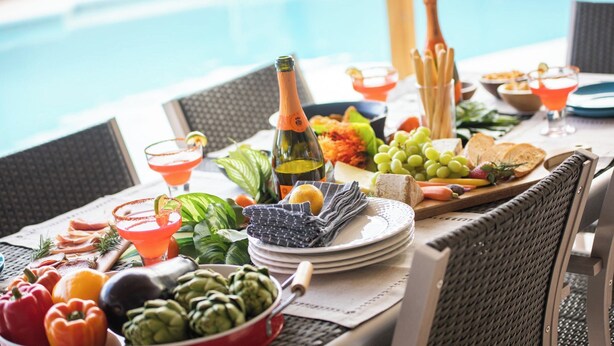 A poolside dining setup with a variety of foods, drinks, and a bottle of wine. - West Ridge by Avantstay Pool, Fire Pit, Al Fresco Dining 7 Mins to Downtown (Scottsdale)