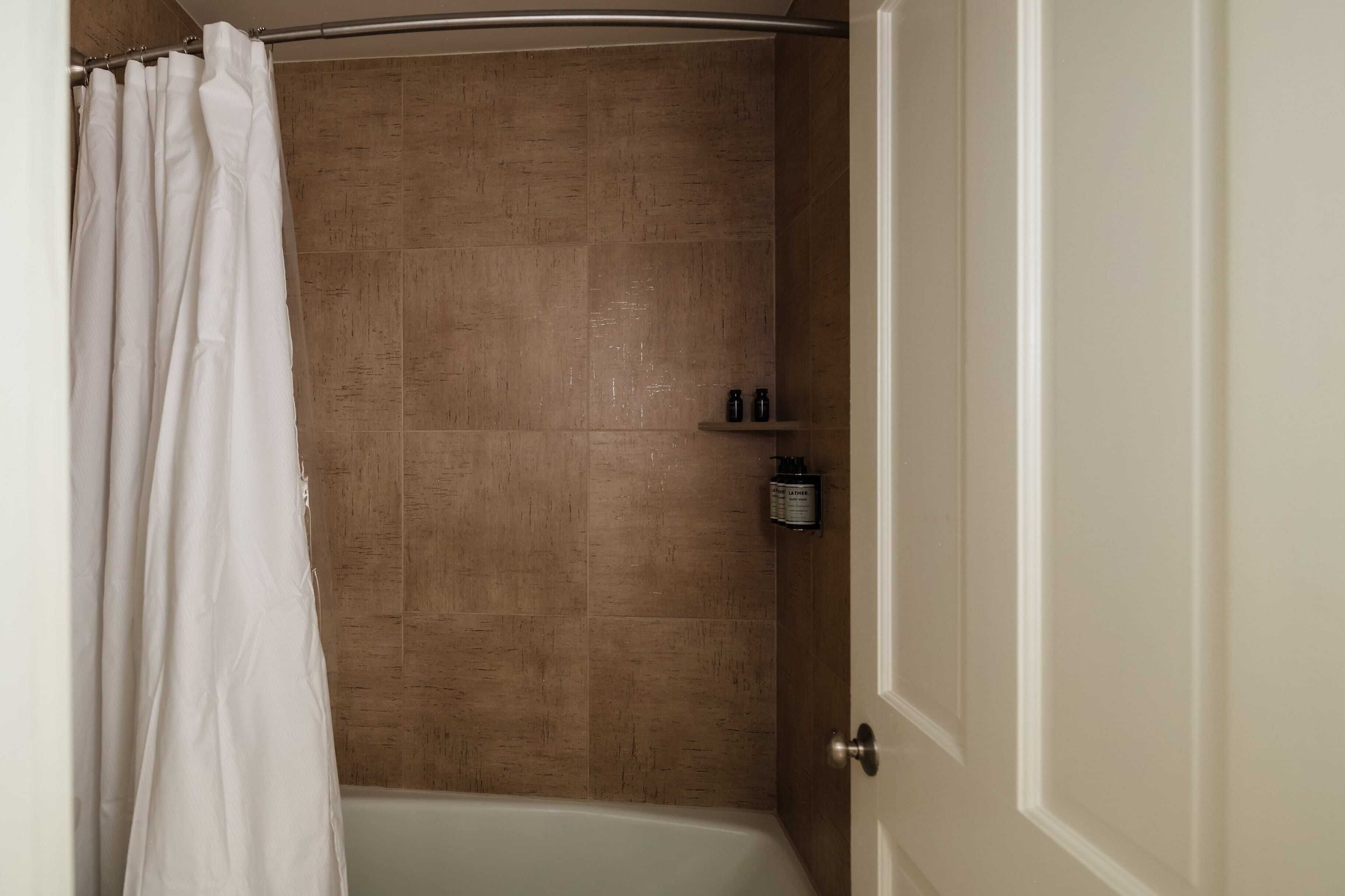 Ein Badezimmer mit Dusche, gefliesten Wänden und einer Tür.