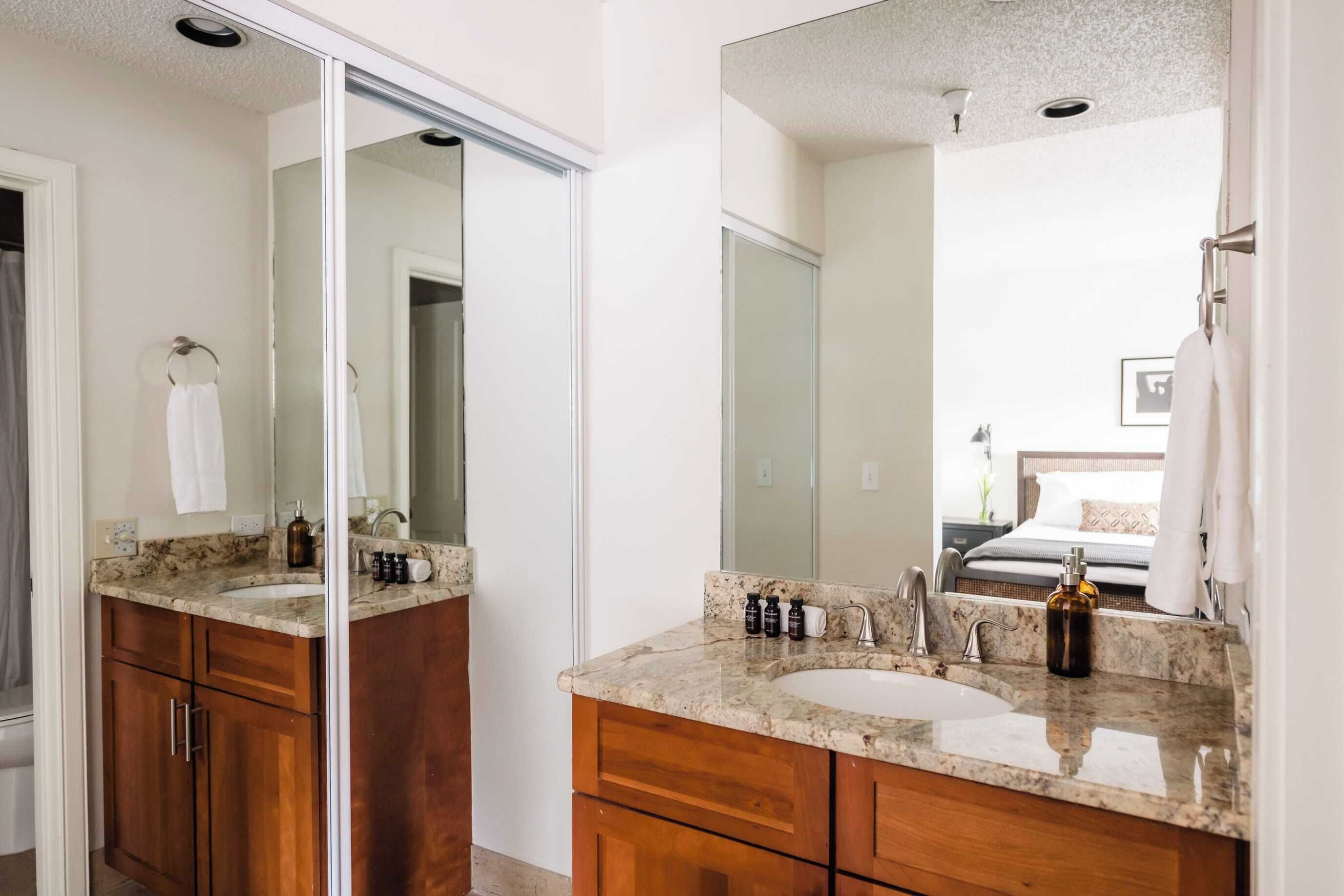 A modern bathroom with a large mirror, a sink, and wooden cabinets.