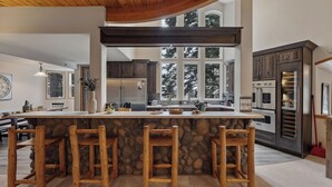 A kitchen with a large island, stone accents, and modern appliances.
