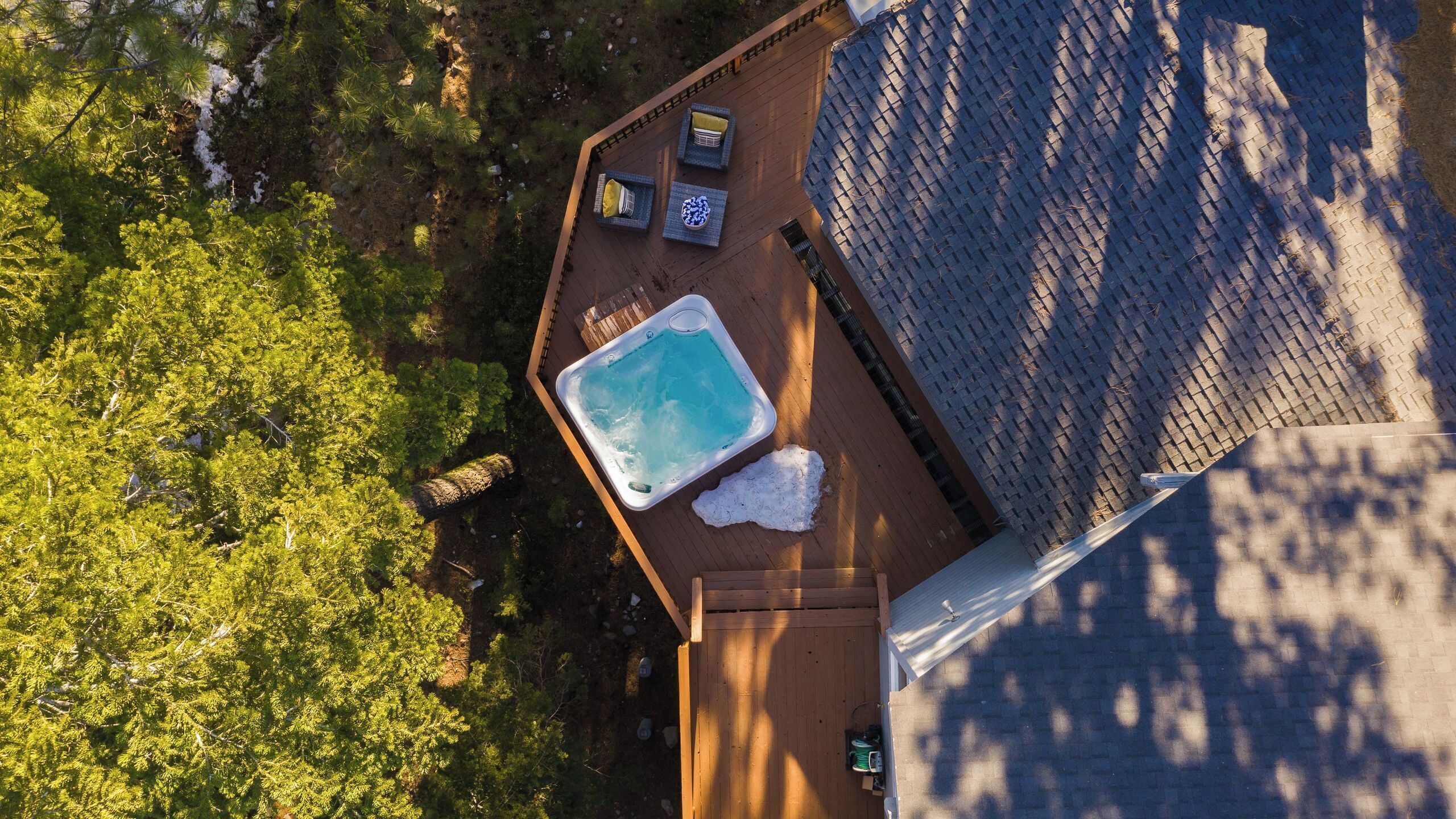 An aerial view of a rooftop with a hot tub, outdoor seating, and a pool.