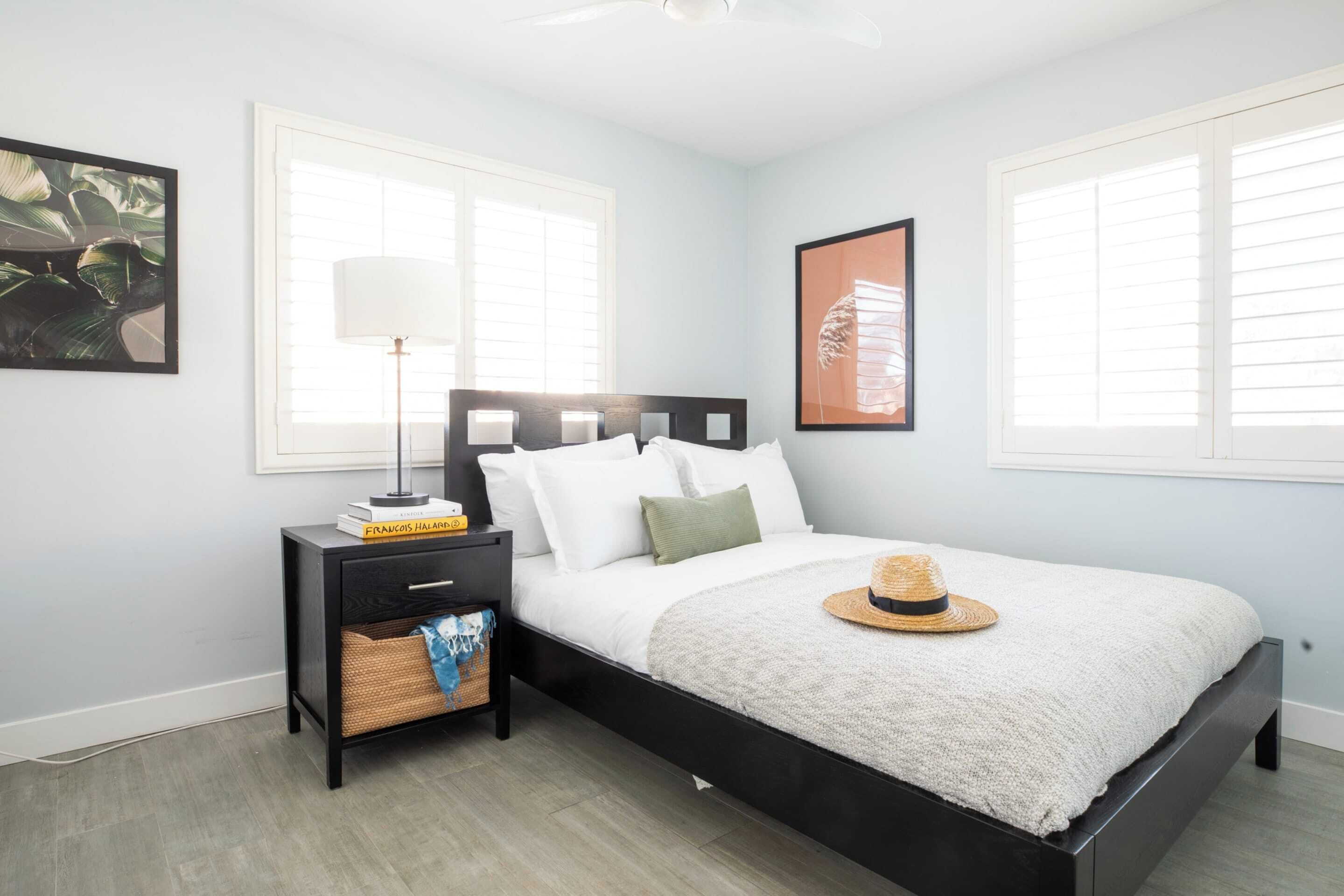 A bedroom with a bed, nightstand, lamp, and wall art.
