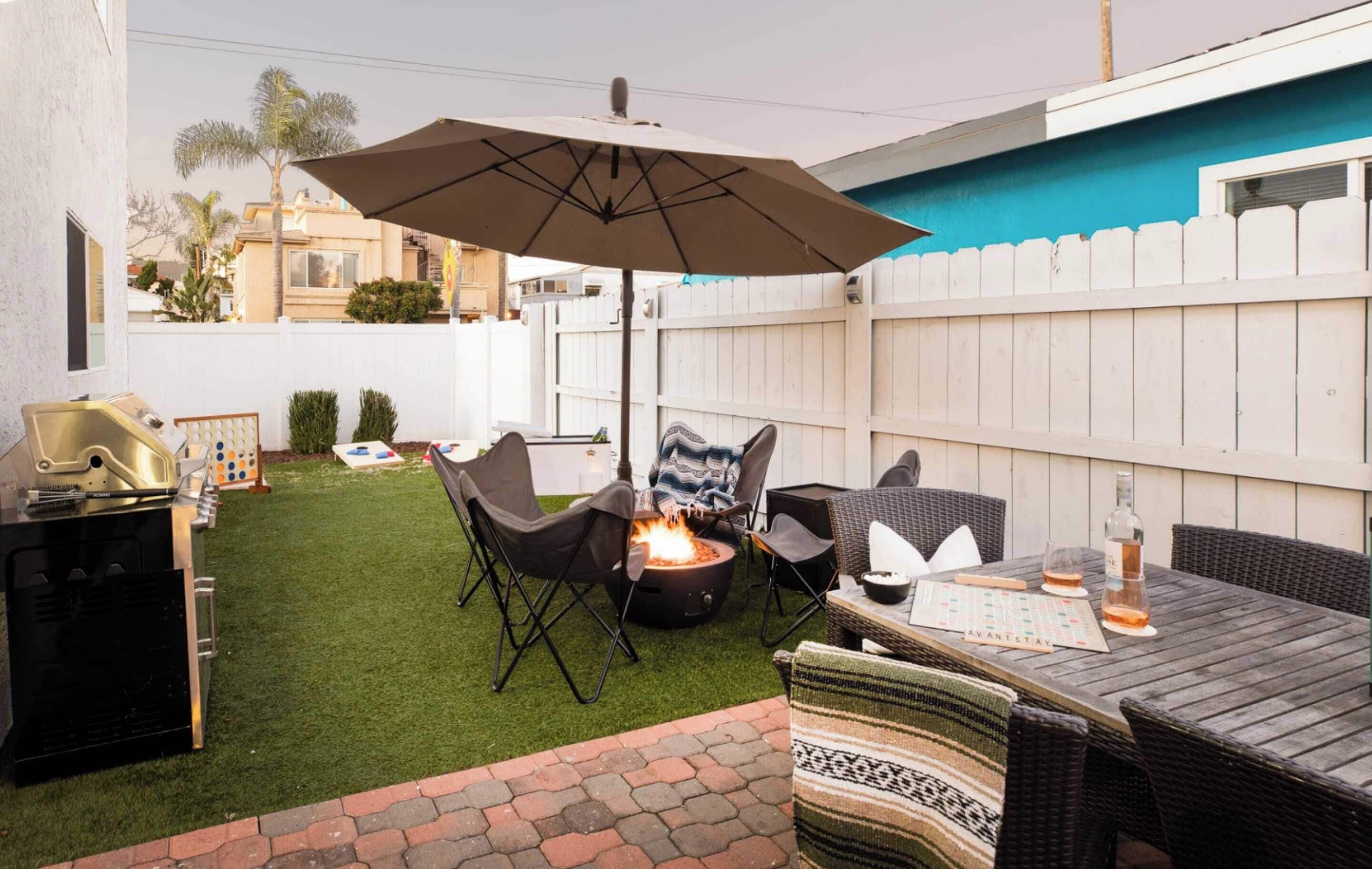 A backyard with a fire pit, outdoor furniture, and a grill.