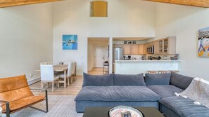 A modern living room with a sofa, a coffee table, and a dining area with chairs.