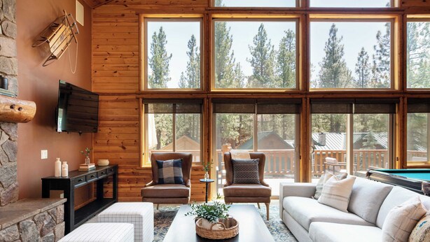 A cozy living room with a stone fireplace, large windows, a pool table, and comfortable seating. - Bernard by Avantstay Luxurious Cabin in Big Bear w/ Hot Tub & Pool Table (Big Bear Lake)