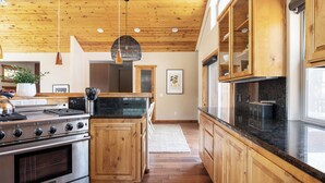A modern kitchen with wooden cabinets, a stove, and a large island. - Bernard by Avantstay Luxurious Cabin in Big Bear w/ Hot Tub & Pool Table (Big Bear Lake)