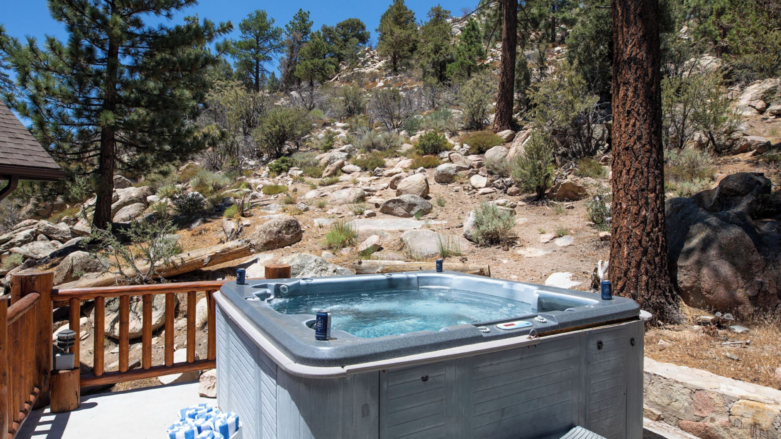 Un jacuzzi en un entorno natural con una terraza de madera y terreno rocoso.