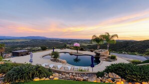 Una piscina con vistas al campo, rodeada de rocas y plantas.