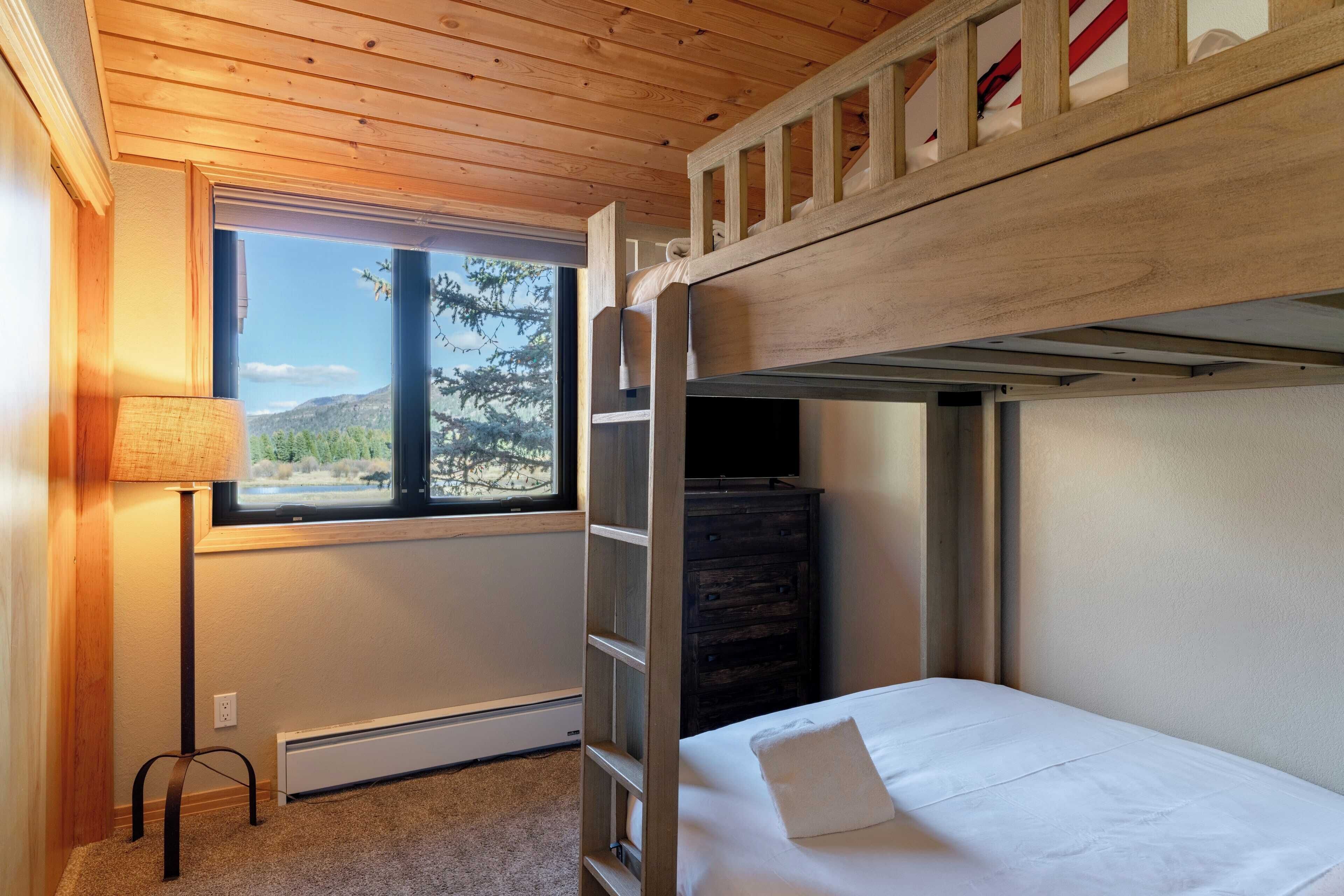 Dormitorio con literas y ventana que ofrece vistas a árboles y montañas.