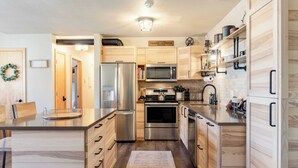 Une cuisine moderne avec des meubles en bois, des appareils en acier inoxydable et un four à micro-ondes encastré.