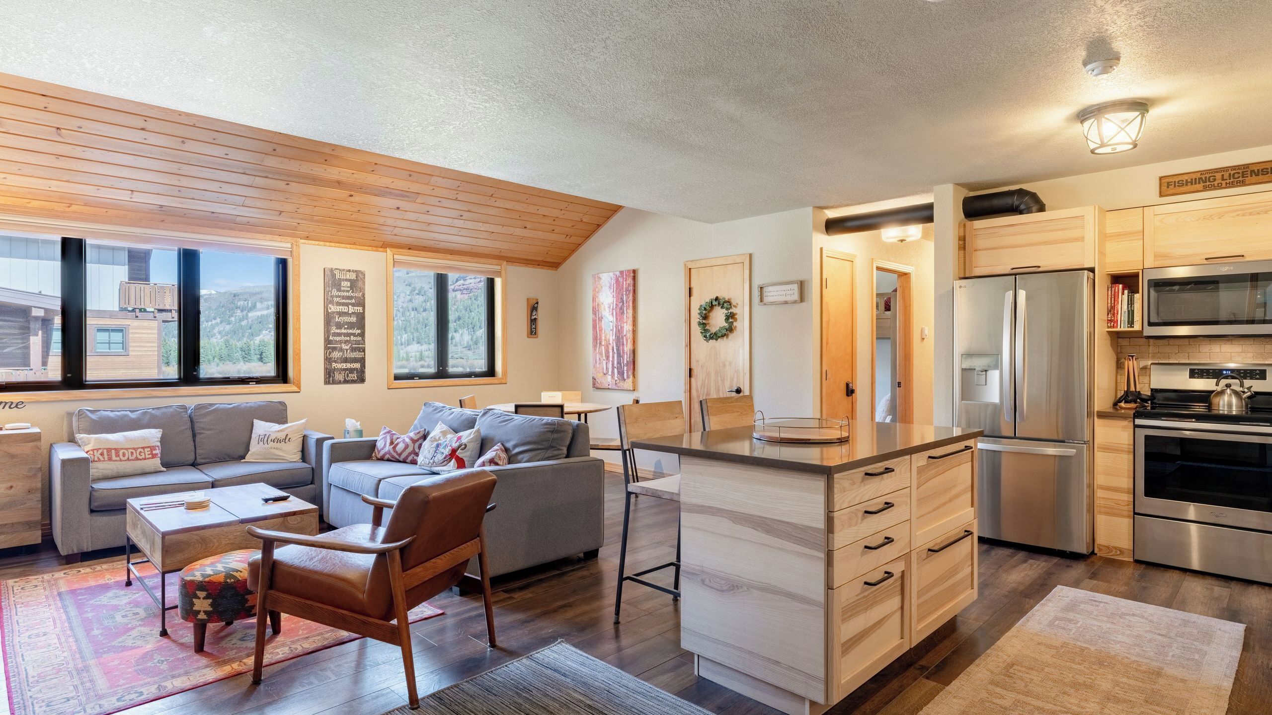 A modern kitchen with a refrigerator, stove, and microwave. There is a dining area with a table and chairs.