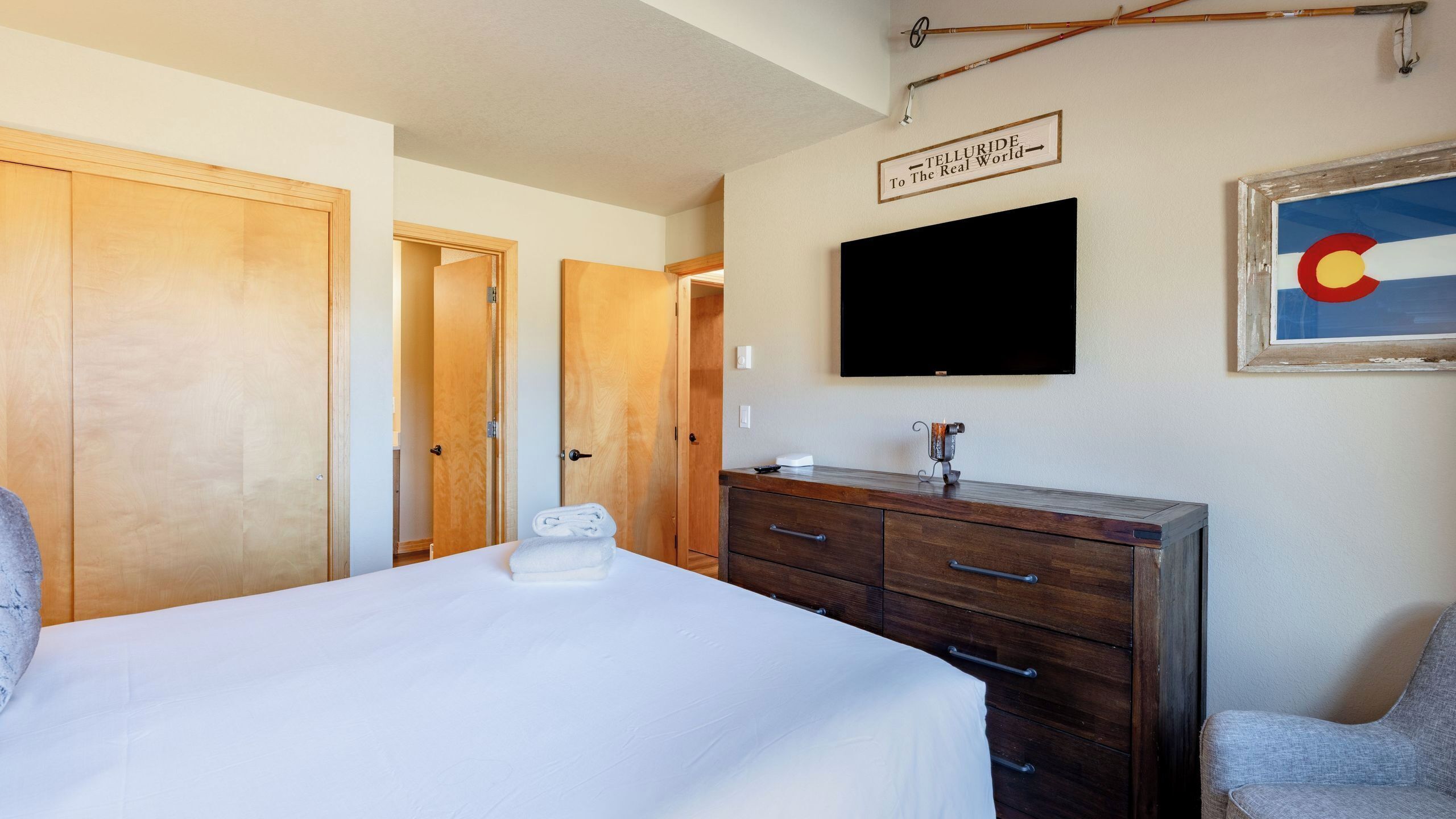 Una habitación de hotel con una cama, un aparador de madera, un televisor y un letrero en la pared.