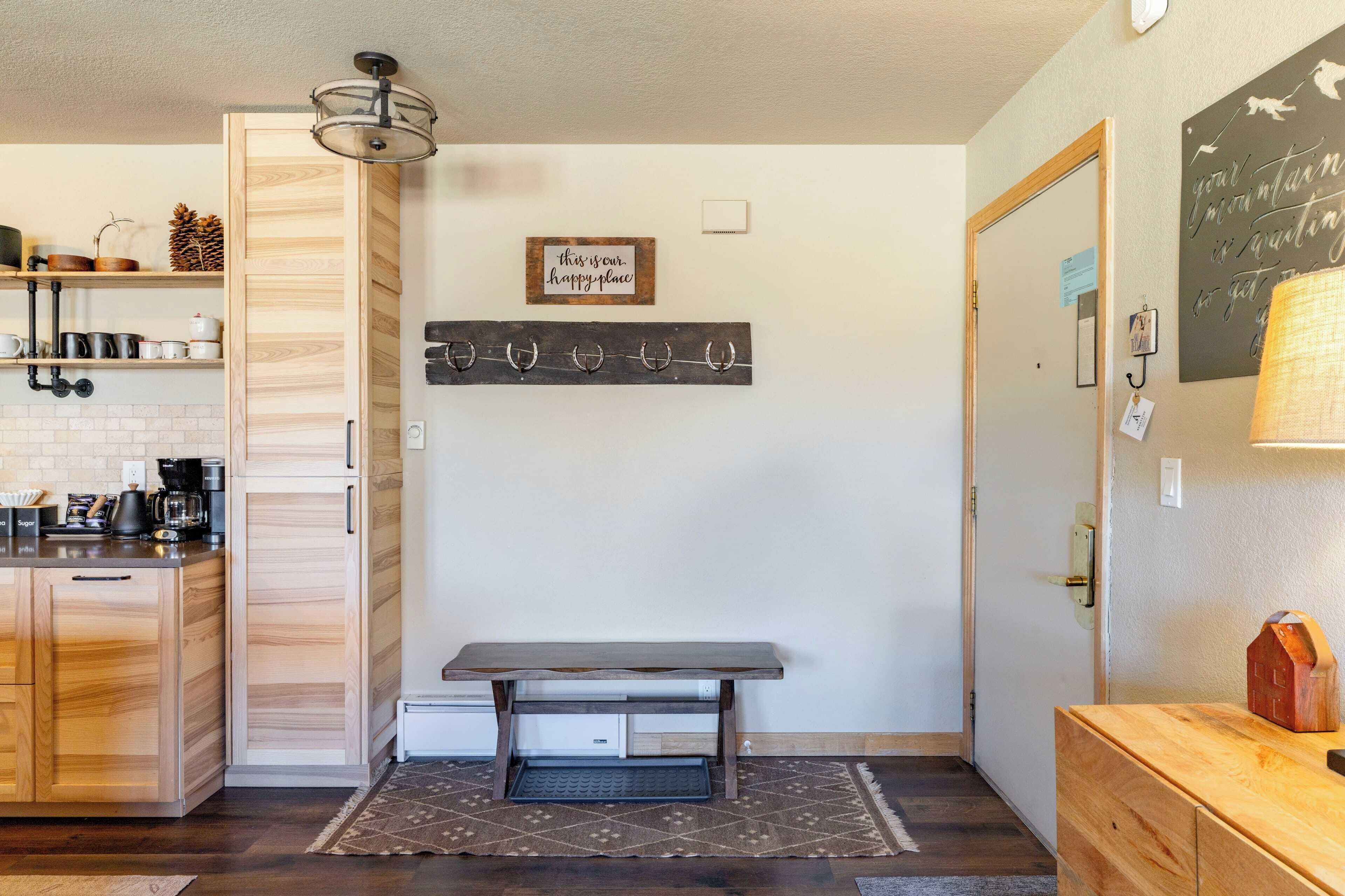 A compact kitchen with wooden cabinets, a built-in coffee machine, and a small dining table.