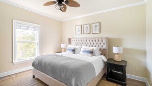 A bedroom with a tufted headboard, a large bed, two bedside tables with lamps, and a ceiling fan. - Fin by Avantstay 9 BR Destin Oasis With Pool & Spa Walk to Beach (Panama City Beach)