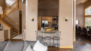 Un vaste espace de vie agrémenté d’un escalier en bois, une cuisine dotée d’un îlot central et un coin repas avec des chaises et une table.