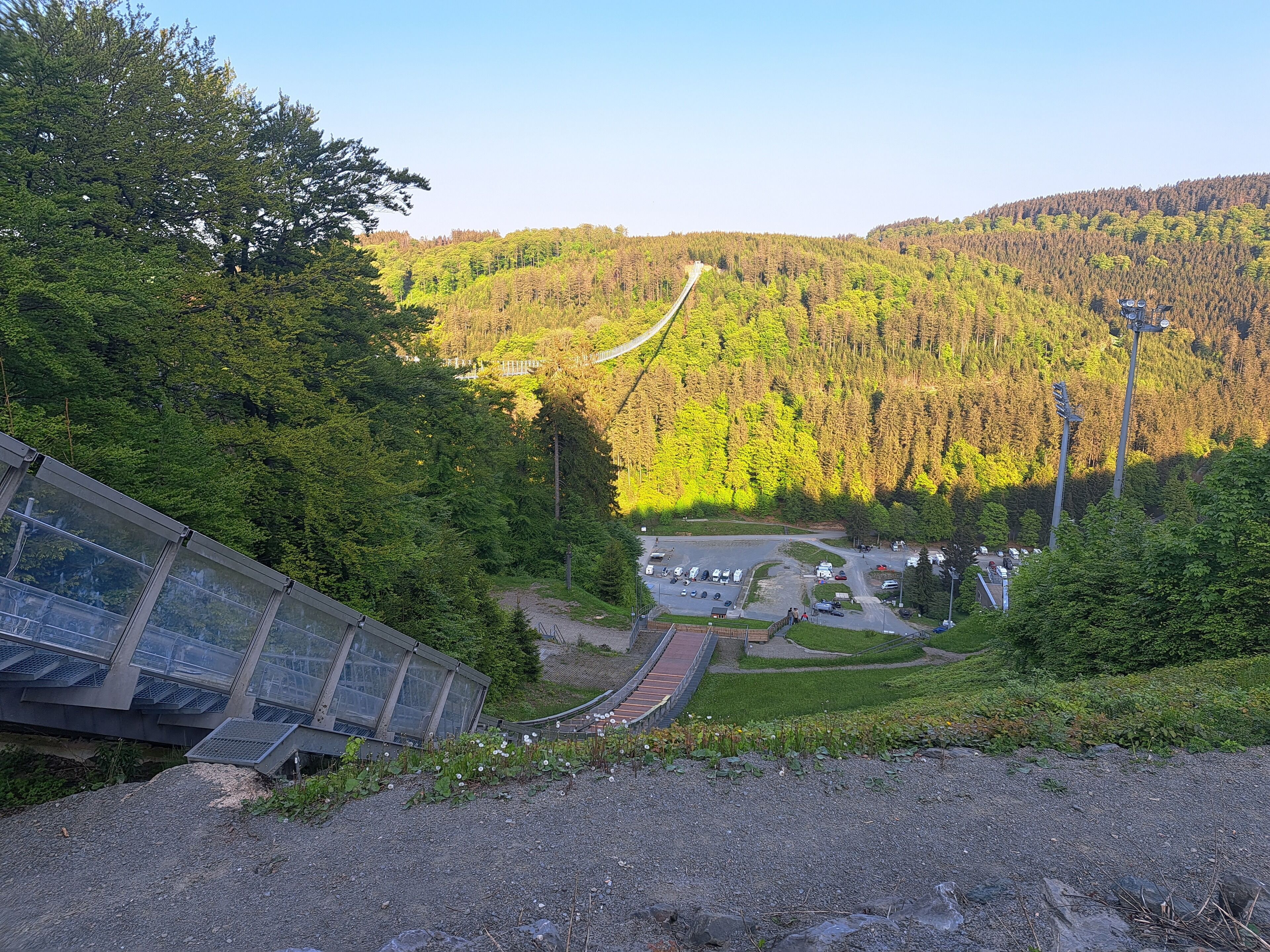 A mountainous landscape with a road leading to a parking area surrounded by trees.