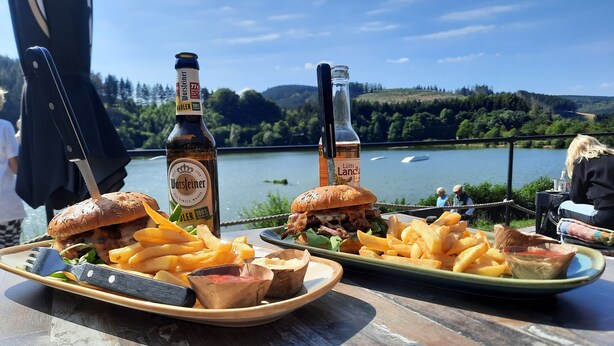 Une table avec deux assiettes de nourriture, une bouteille de bière et un couteau.