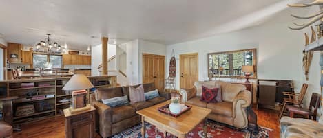 A spacious living room with a fireplace, a large rug, and a view of the outdoors.