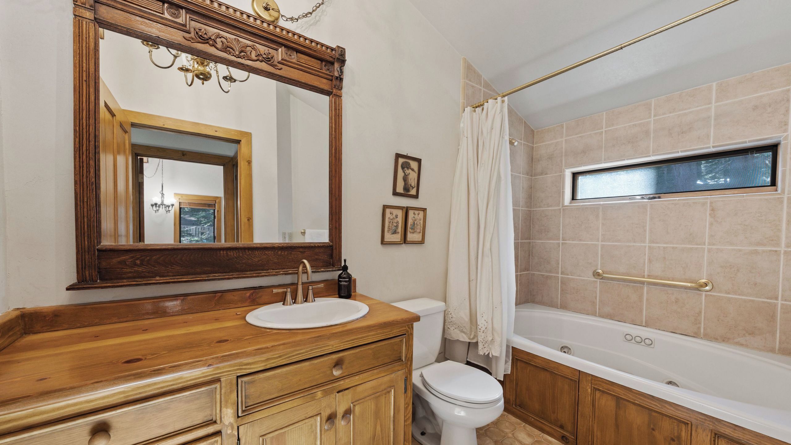 Une salle de bain avec un meuble-lavabo en bois, un lavabo blanc, des toilettes, une baignoire et un grand miroir.