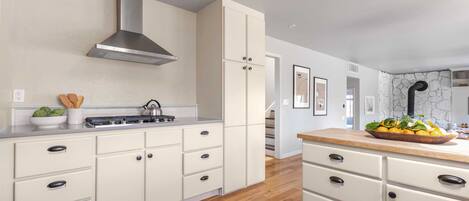 Una cocina moderna con armarios blancos, una campana de acero inoxidable y una encimera de madera.