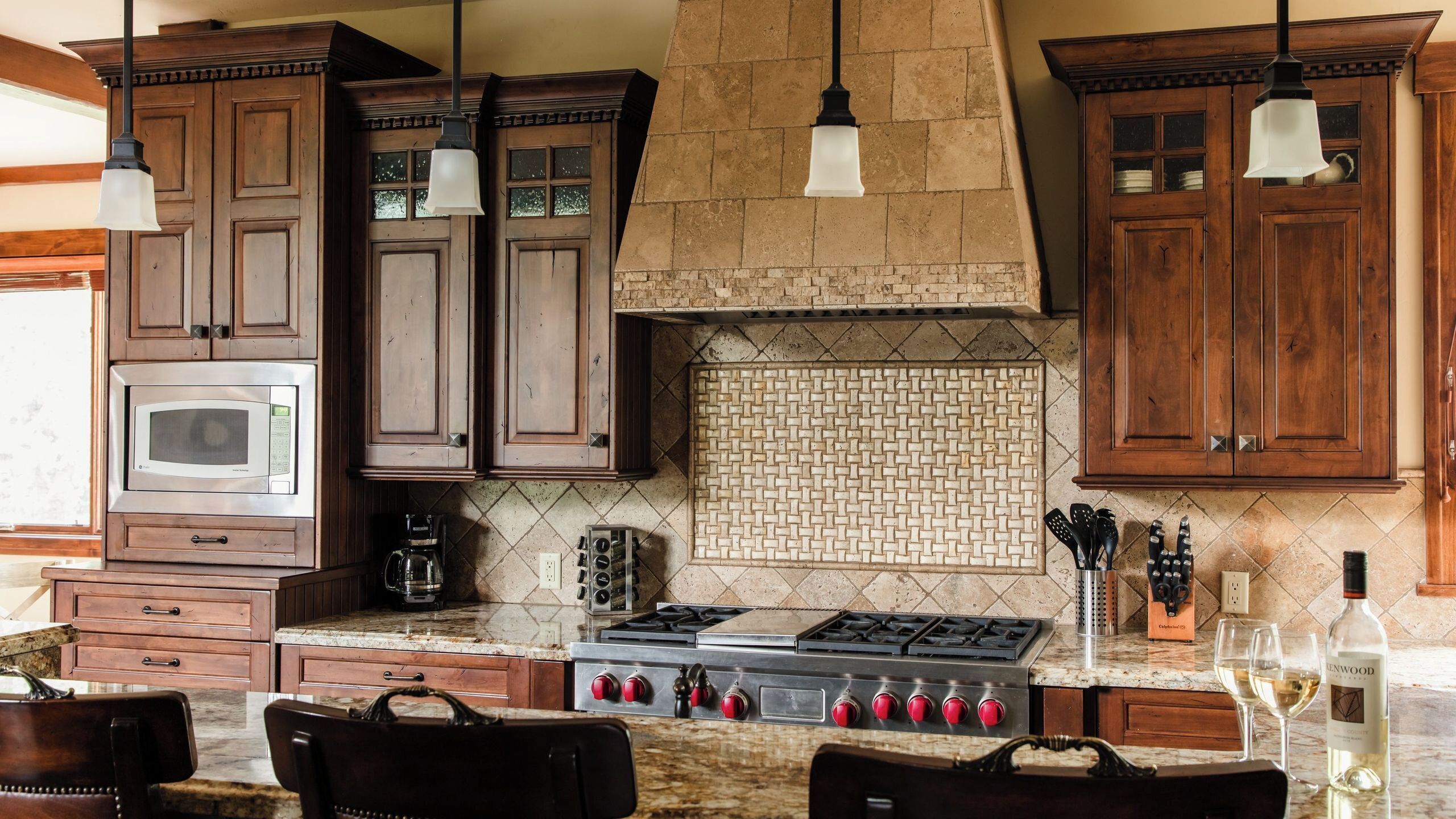 A kitchen with wooden cabinets, a microwave, a stove, and hanging lights.