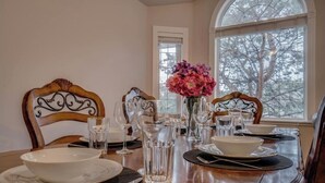 A dining table set with white plates, bowls, and clear glasses, with a vase of pink flowers in the center. - Big family home w/ Deck, Ping Pong, BBQ & Garage (Edmonton)