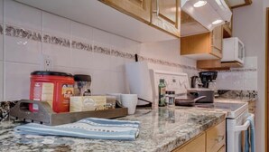 A kitchen with granite countertops, a microwave, a coffee maker, and various kitchen appliances. - Big family home w/ Deck, Ping Pong, BBQ & Garage (Edmonton)