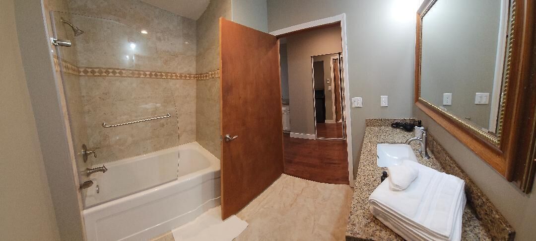 A bathroom with a bathtub, a sink, and a mirror.