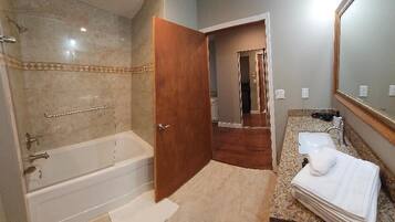 A bathroom with a bathtub, a sink, and a mirror.