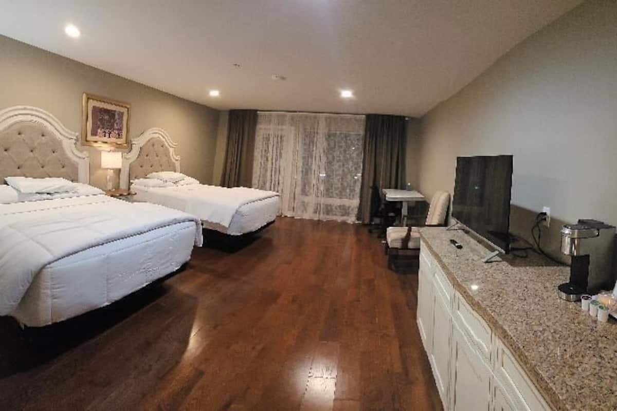 A hotel room with two beds, a desk, a TV, and a coffee machine.