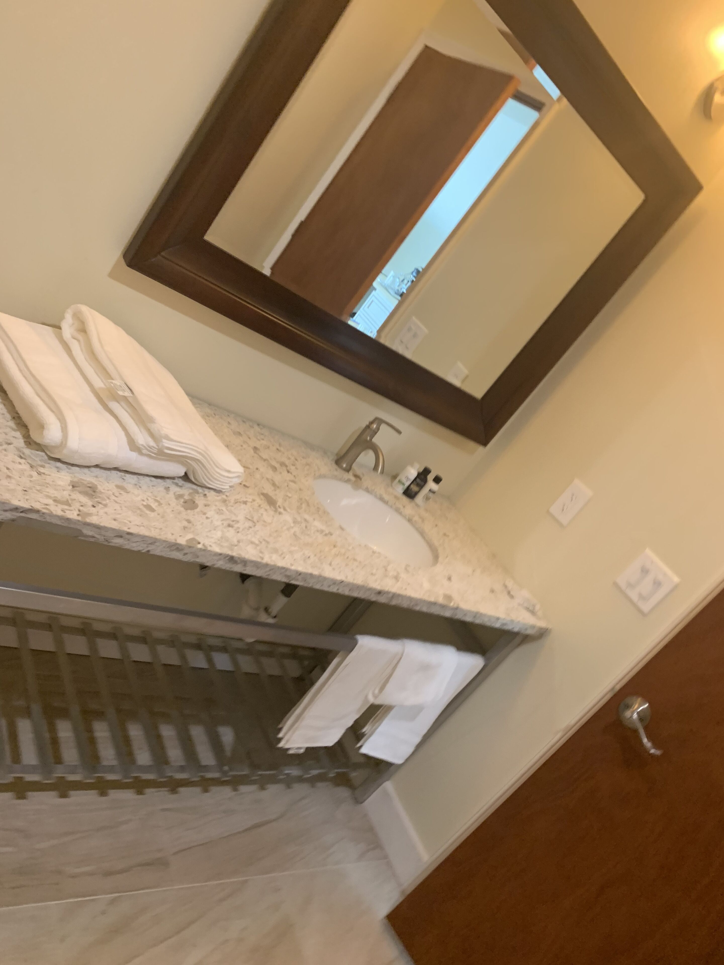 A bathroom with a marble sink, a mirror, and a towel rack.