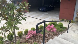 A modern building with a garage, a staircase, and a small garden with pink flowers. - Lakeview Hotel (Kirkland)