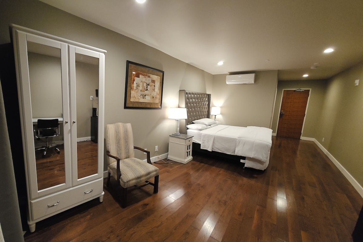A bedroom with a bed, a chair, a wardrobe, and a nightstand.