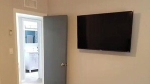 Een slaapkamer met een bed, een televisie aan de muur en een deur naar een badkamer.