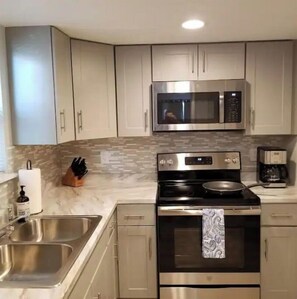 Fully equipped kitchen with stainless steel appliances, two sinks, and a coffee maker.