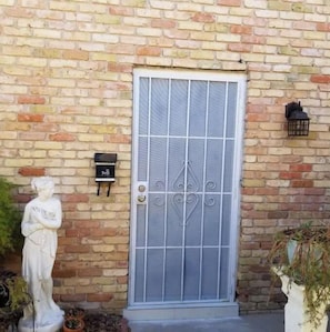 A charming entrance with a decorative metal grille, a mailbox, and a potted plant.